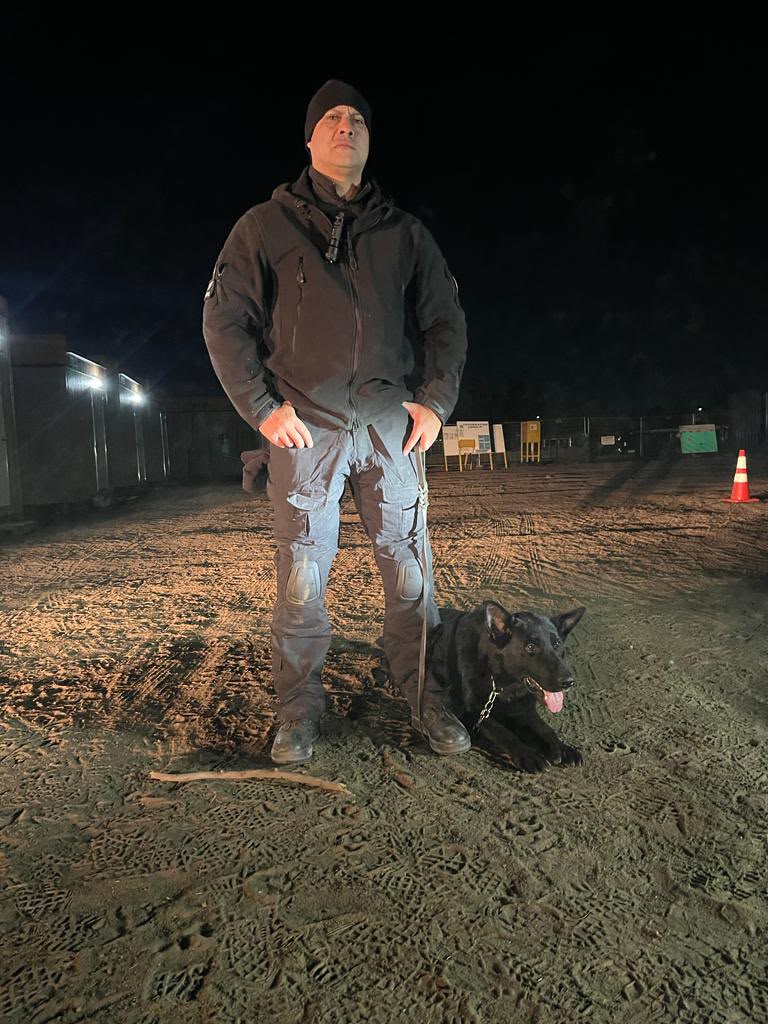 Guardia de seguridad con perro en turno de noche en planta industrial